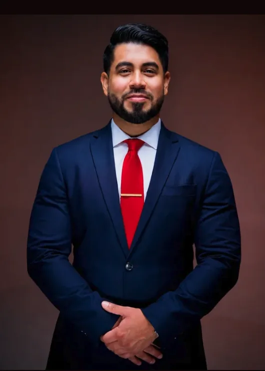 Alvaro Flores, attorney, in a navy suit and red tie.